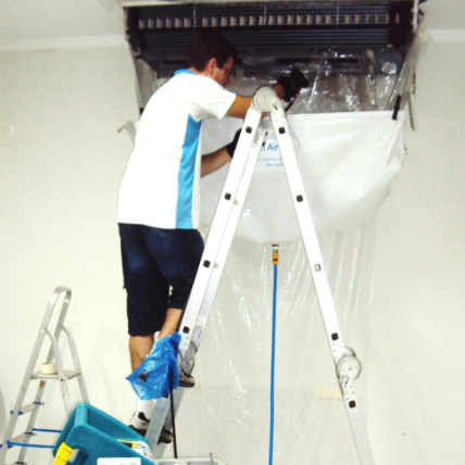 Técnico limpando duto de ar condicionado de teto com escada